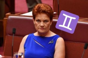 Pauline Hanson in parliament wearing a blue dress with a purple Gemini symbol next to her head
