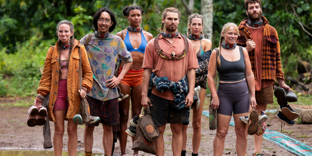 The cast of Australian Survivor 2025 stands together in the jungle, holding their shoes and gear