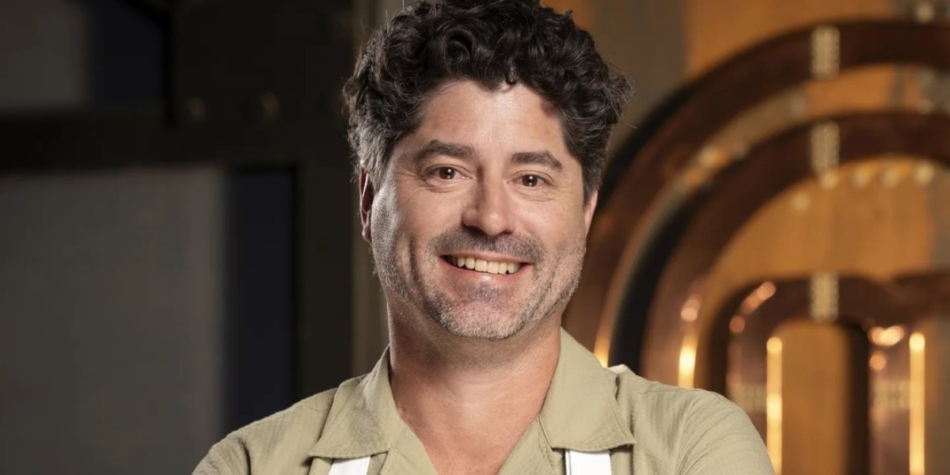Ben MacDonalds smiles warmly in front of the MasterChef Australia 2025 logo, wearing a beige shirt and apron